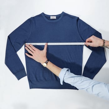 hands showing how to measure knitwear chest